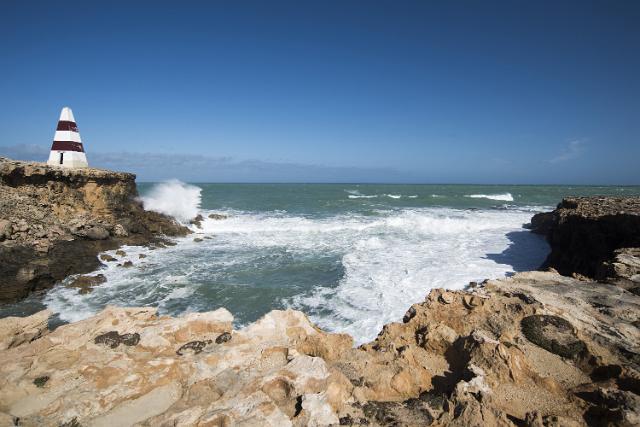 The Robe Obelisk, Guichen Bay, South Australia with waves pounding the rocks of the headland in heavy surf causing erosion below this historic landmark