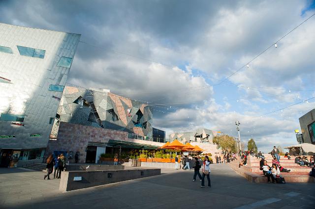 People walking through Federation Square, Melbourne as they enjoy a cloudy summer day in this cultural precinct in the centre of the CBD area of the city offering a variety of recreational activities