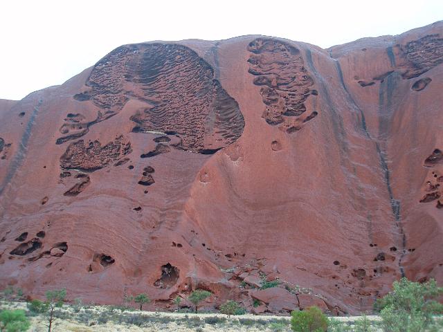 weathered rock on the side of uluru that looks like a head