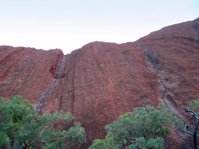 looking up at towering red cliffs from the base of uluru - ayres rock