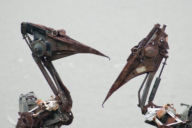 Scrap metal pelican sculptures on the banks of the Brisbane River, closeup detail of the structure of their heads against a hazy blue sky