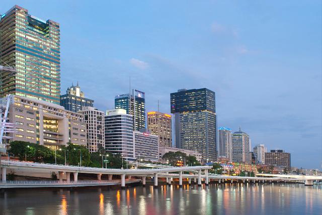 Central Brisbane waterfront at night with the colourful lights of the CBD reflected in the water of the Brisbane River at twilight