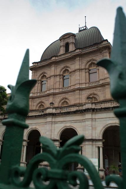 View through a wrought iron gate of the exterior facade of Brisbane Parliament House which is the seat of the Queensland Legislative Assembley