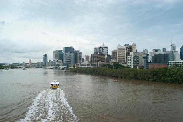 Ferry on the Brisbane River travelling upriver at speed leaving a wide wake as it approaches the central CBD of the city