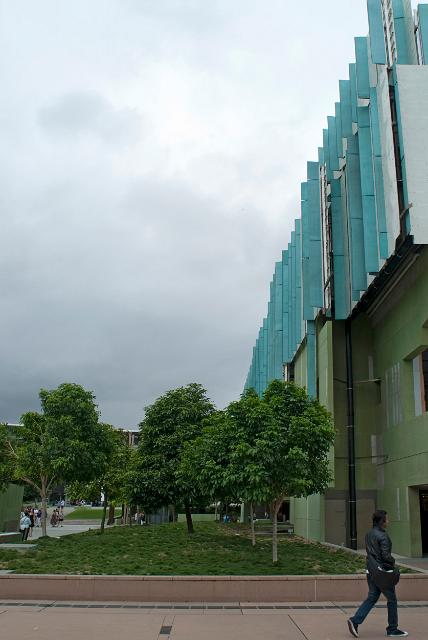 Exterior facade of the Queensland State Library in Brisbane, Australia showing the gardens and a pedestrian walking past