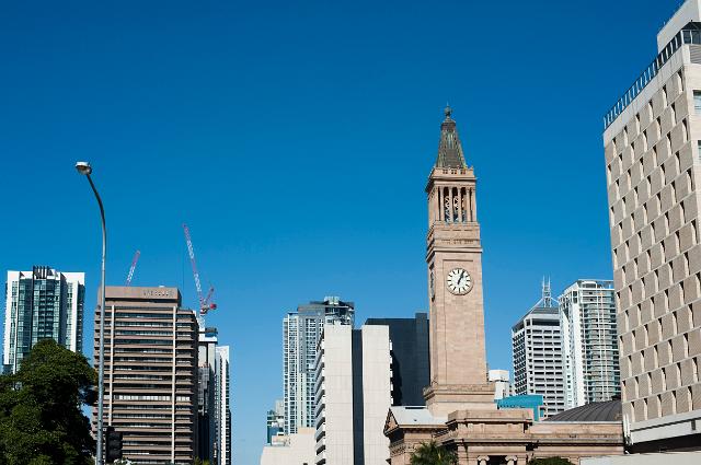 Brisbane skyline of modern highrise buildings in the CBD with the historical stone City Hall Clock Tower against a clear sunny blue sky