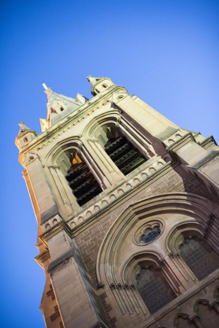 Low angle view of the exterior facade of St Peters Tower or spire on the cathedral , Adelaide, Australia against a blue sky