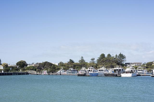 Motorboats and fishing boats moored in the sheltered harbour at Robe, South Australia looking across the water towards the town and leafy green trees